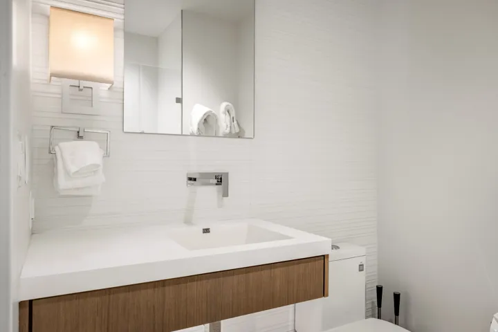 Modern vanity featuring a wood-finish cabinet, integrated basin, and chrome wall-mounted faucet