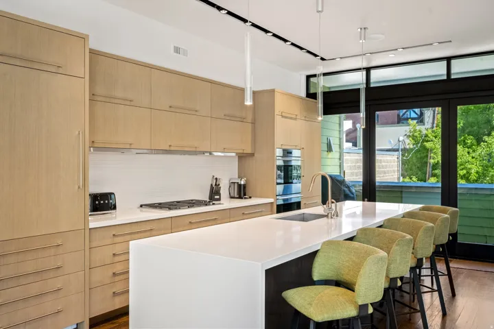 Modern kitchen featuring light wood-finish cabinetry, integrated oven, and a built-in cooktop