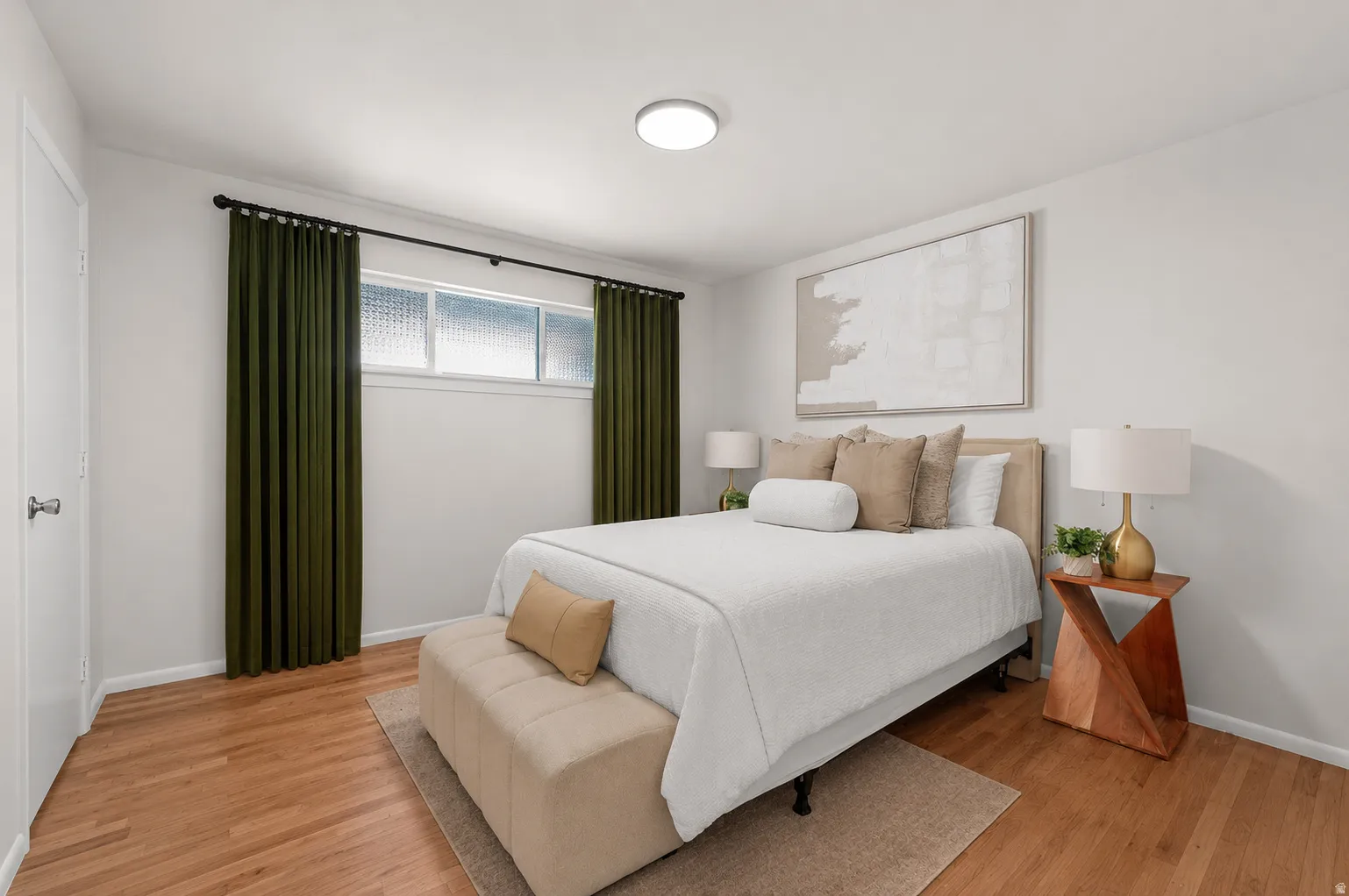 Wood-finish flooring, white walls, and a flush-mount ceiling light
