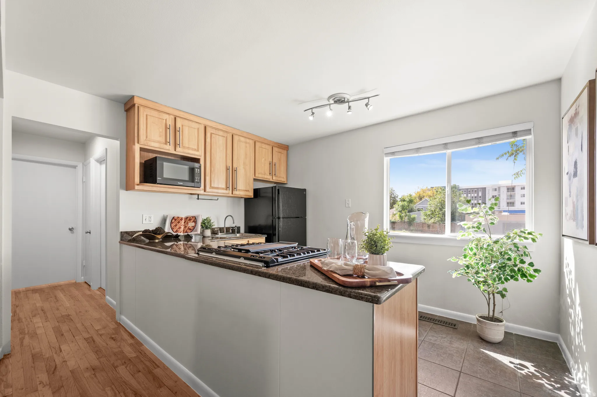 Kitchen featuring wood cabinetry, granite-style countertops, stainless steel gas range, and a track lighting fixture