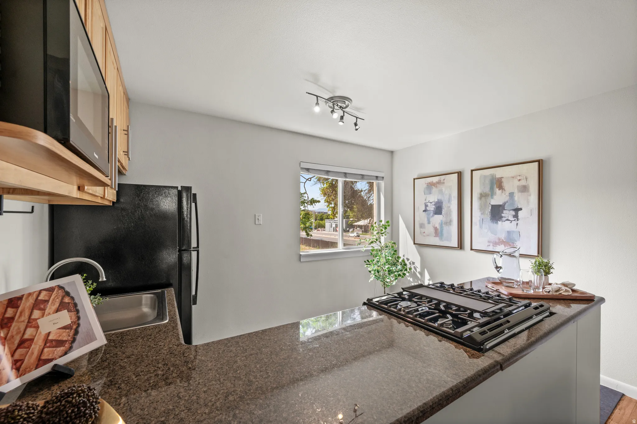 Kitchen featuring wood-finish cabinetry, black appliances, built-in microwave, a built-in cooktop, and polished stone-finish countertops