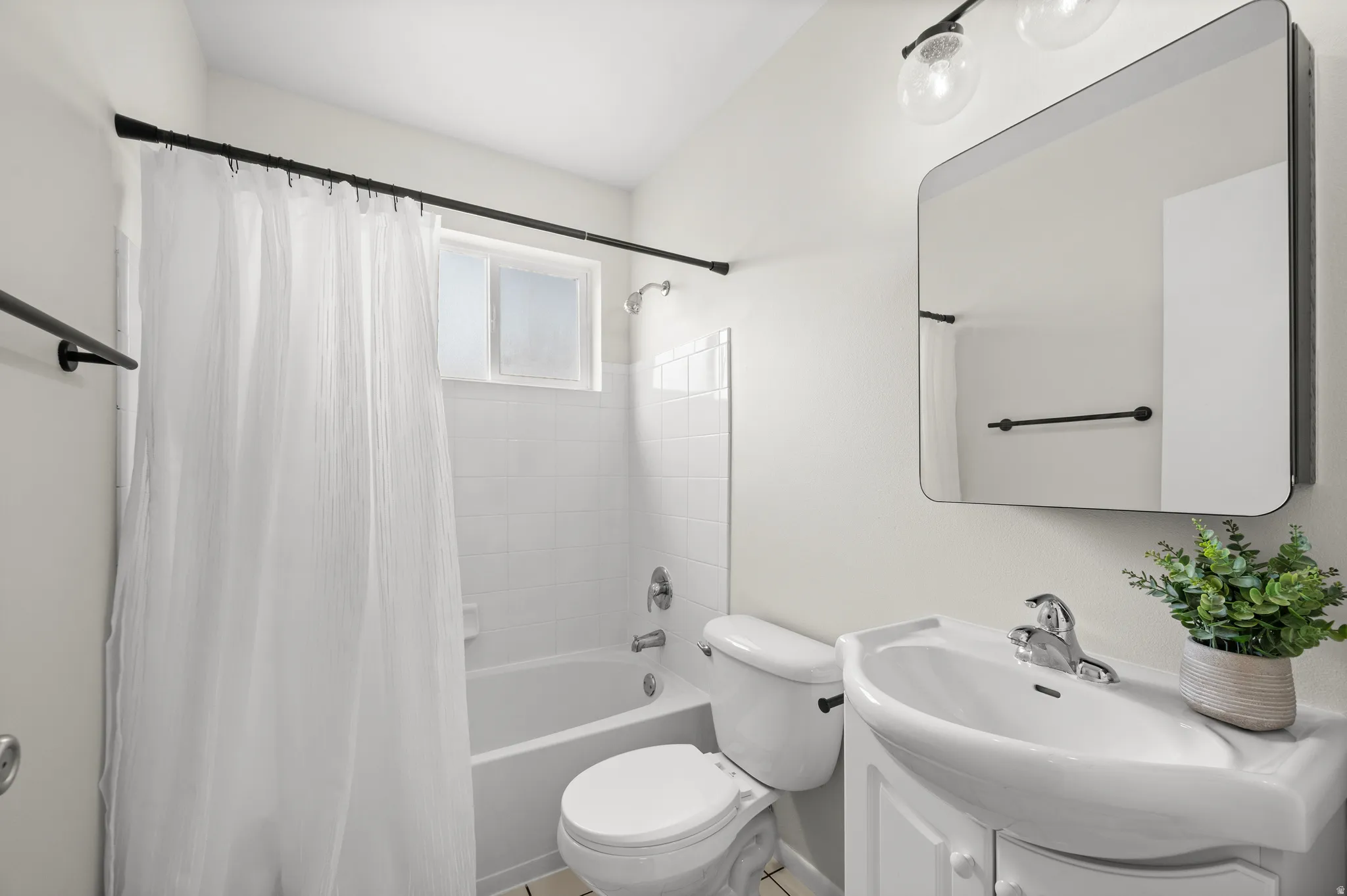 Full bathroom featuring a white tub, white tiled shower surround, recessed window, and a vanity with an integrated sink