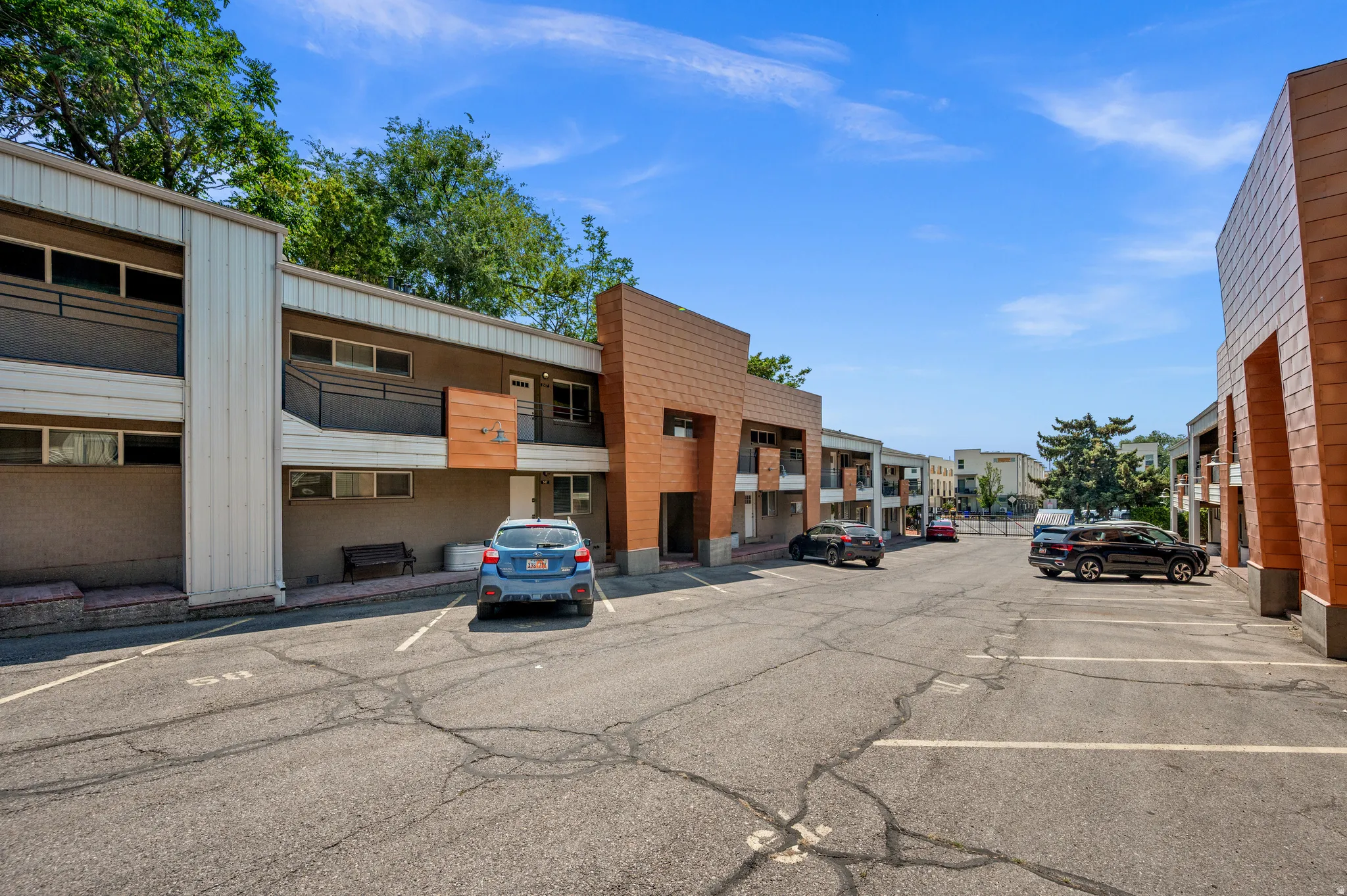 Property exterior featuring a combination of brick, wood-finish, and painted siding, with private balconies and a paved parking area