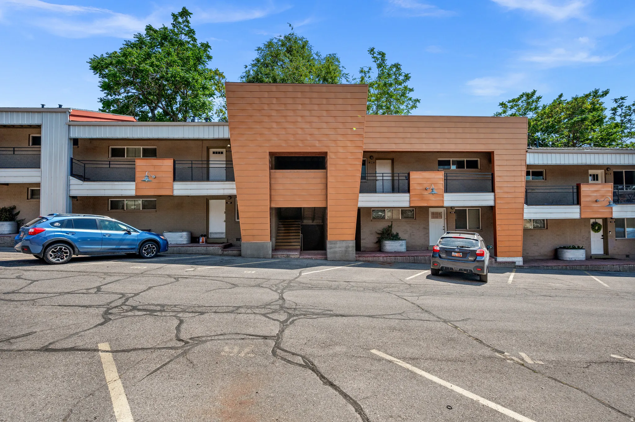 Multi-story exterior with a mix of siding materials, featuring private balconies with black railings, and an integrated central staircase