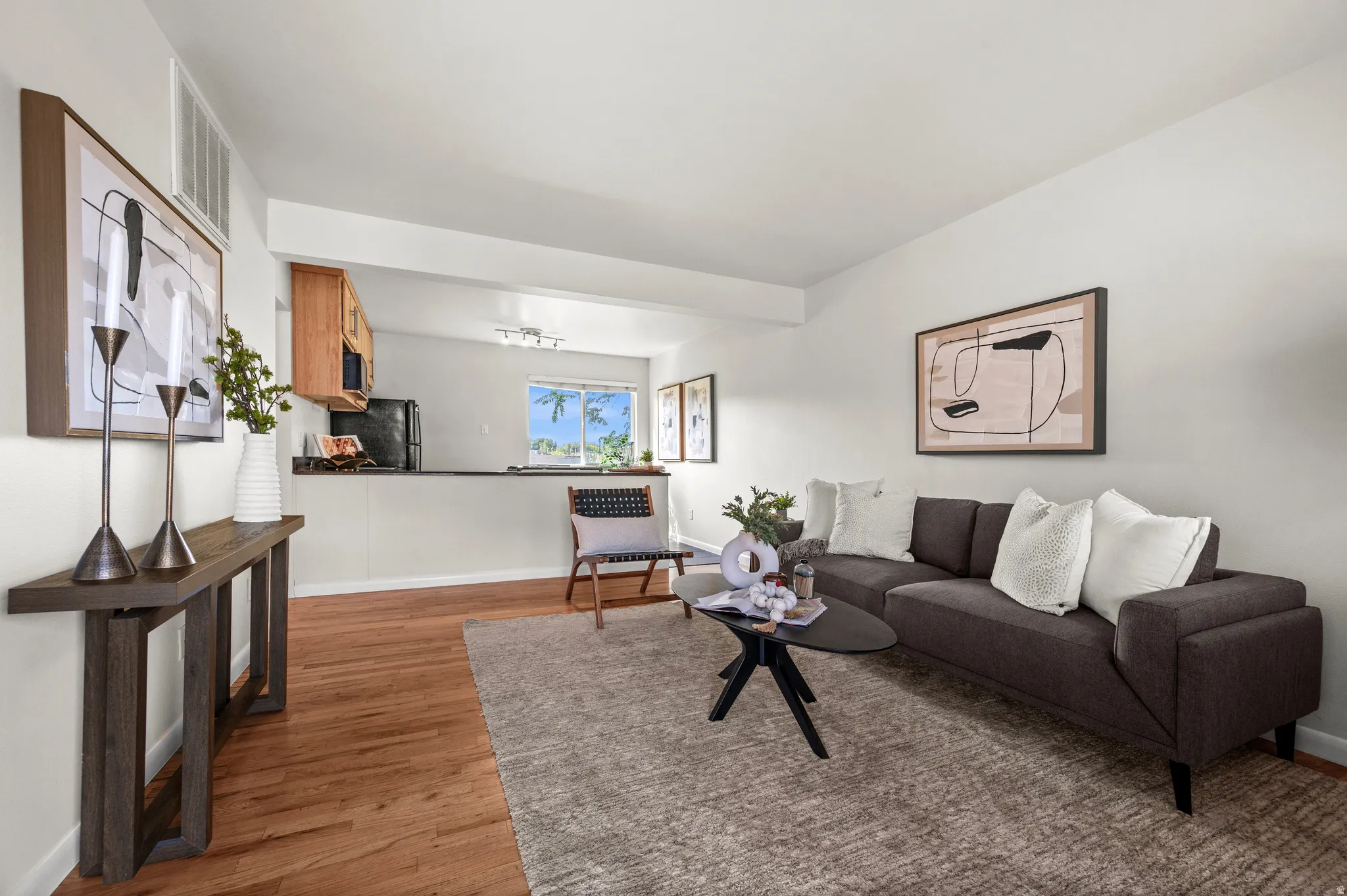 Open-concept living area featuring wood-finish flooring, a kitchen pass-through, and neutral wall tones