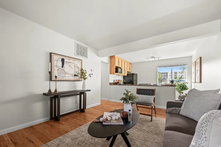 Open-concept living space with wood-finish flooring, a kitchen featuring wood cabinetry and black appliances.