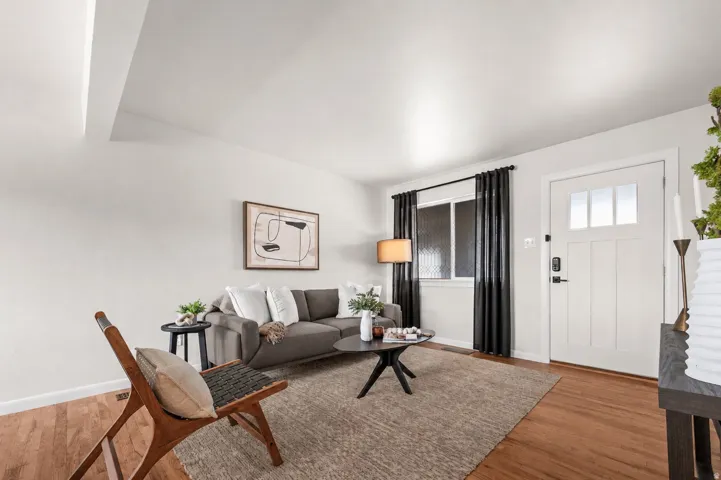 Hardwood flooring, white paneled entry door with clear glass lites, and a window with textured glass