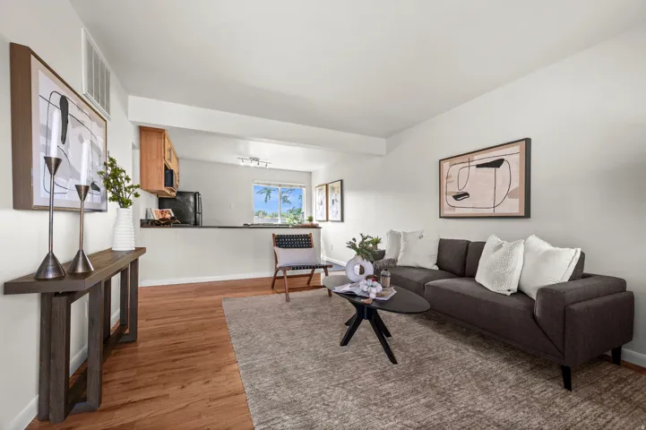 Open-concept living area featuring wood-finish flooring, a kitchen pass-through, and neutral wall tones