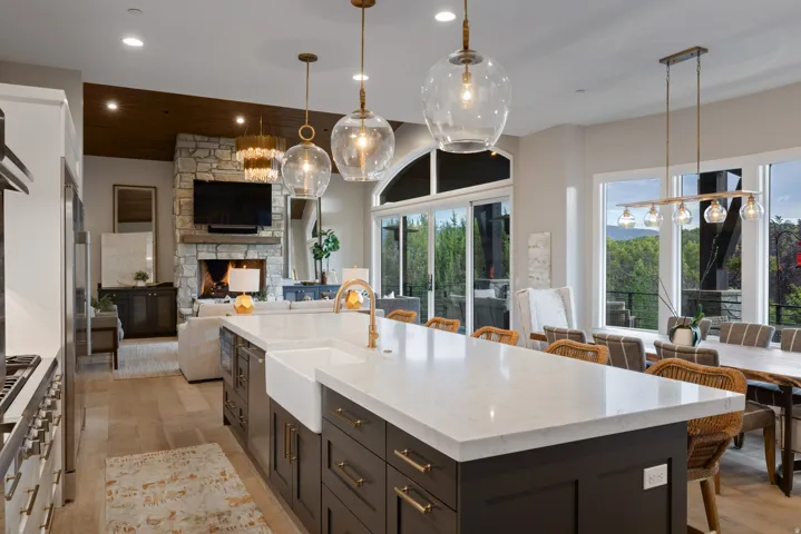 Gourmet kitchen with a large island featuring a built-in sink, stone countertops, and pendant lighting