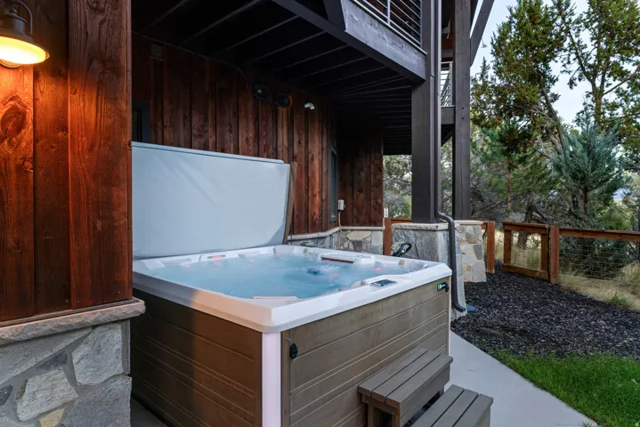Outdoor spa with built-in steps, wood-paneled siding, stone accents, and exterior lighting
