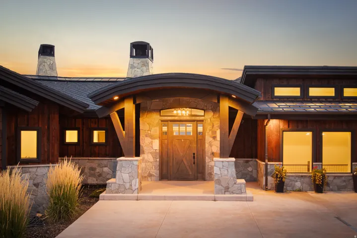 Stone and wood exterior with a covered entry, dark wood-finish door, and integrated lighting