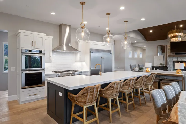 Gourmet kitchen featuring stainless steel appliances, double ovens, a gas range with an exhaust hood, and a large island with a quartz countertop