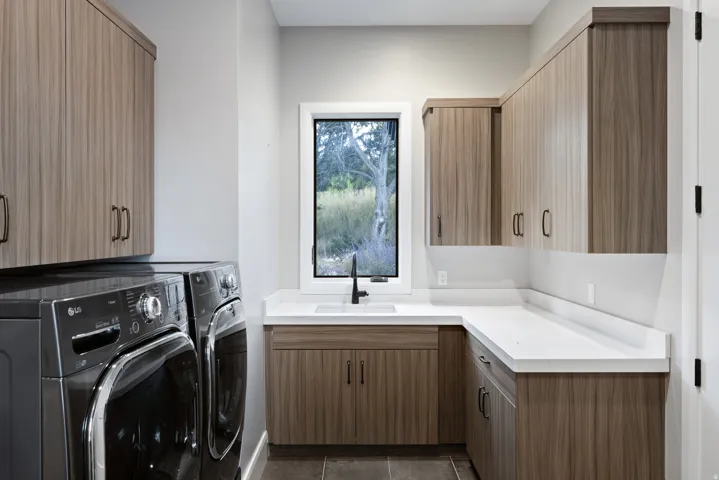 Built-in cabinetry with wood-finish doors, white countertops, and an undermount sink with a matte black faucet