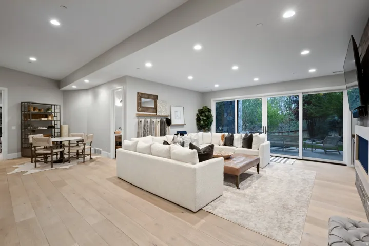 Recessed lighting illuminates the open-concept living space with light-tone wood-finish flooring