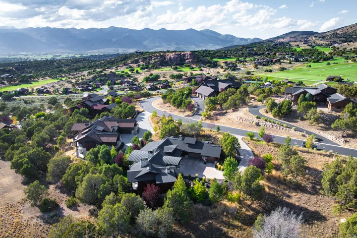 Winding roads and natural landscaping surround the property, featuring a multi-level roofline and natural wood siding