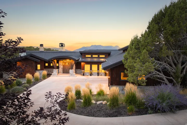 Wood-shingle exterior with stone accents, featuring a curved driveway and integrated landscaping
