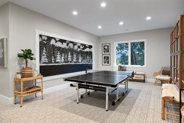 Recessed lighting illuminates a spacious room featuring patterned carpet flooring