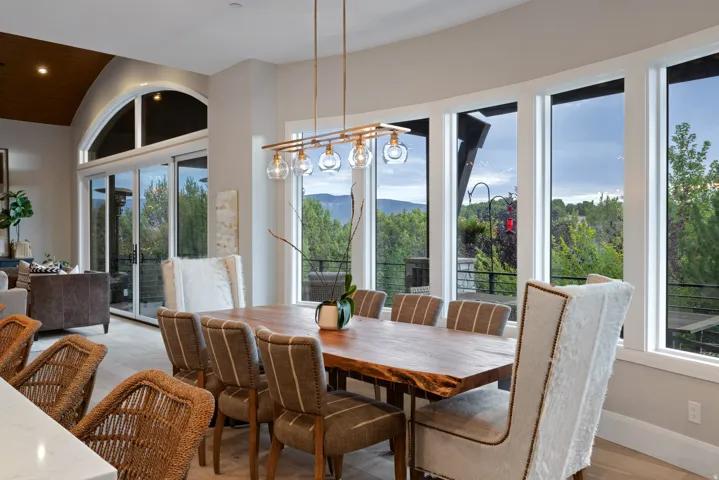 Dining area with a live-edge wood table, a linear pendant light fixture, and large windows