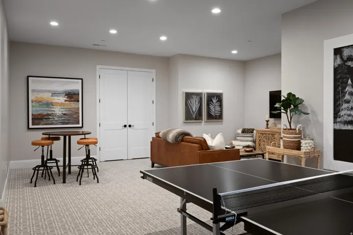 Recessed lighting illuminates the neutral wall tones and patterned carpeting, complemented by double panel doors with black hardware