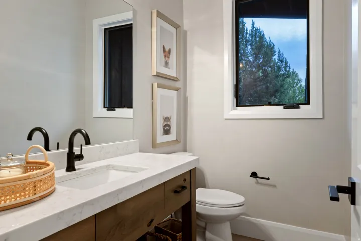 Vanity with integrated sink, stone countertop, wood-finish cabinetry, and matte black fixtures