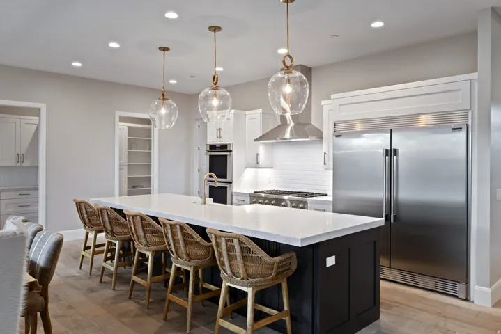 Open-concept kitchen featuring a large island, contemporary pendant lighting, stainless steel appliances, and wood-finish flooring