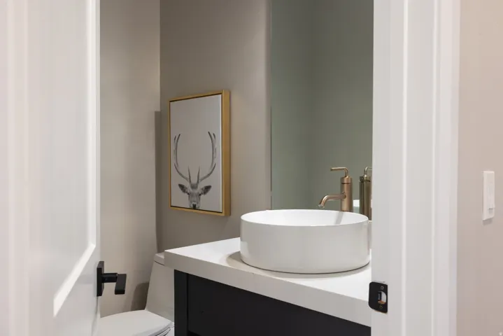 Vanity with a white vessel sink, a gold-tone faucet, and a quartz countertop