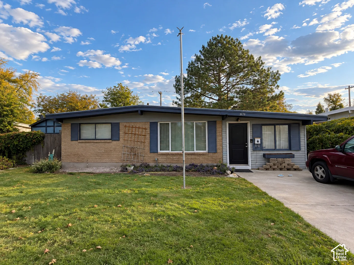 Brick and siding exterior with blue window shutters, a dark entry door, and a concrete driveway
