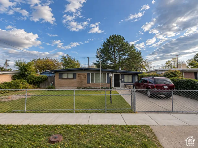 Brick exterior with dark shutters, chain-link fence, and paved driveway