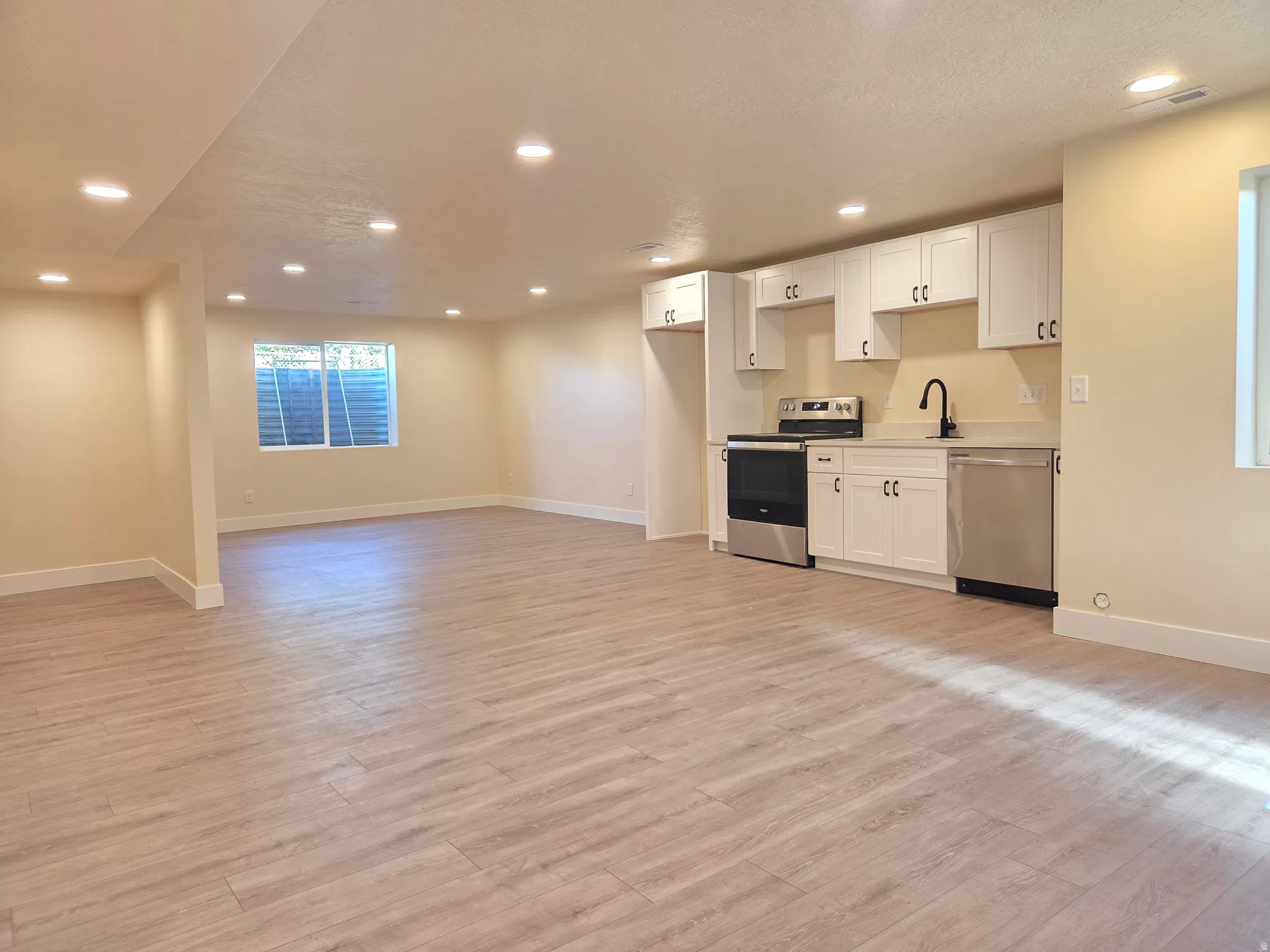 Open-concept living space featuring wood-finish flooring, recessed lighting, and a window