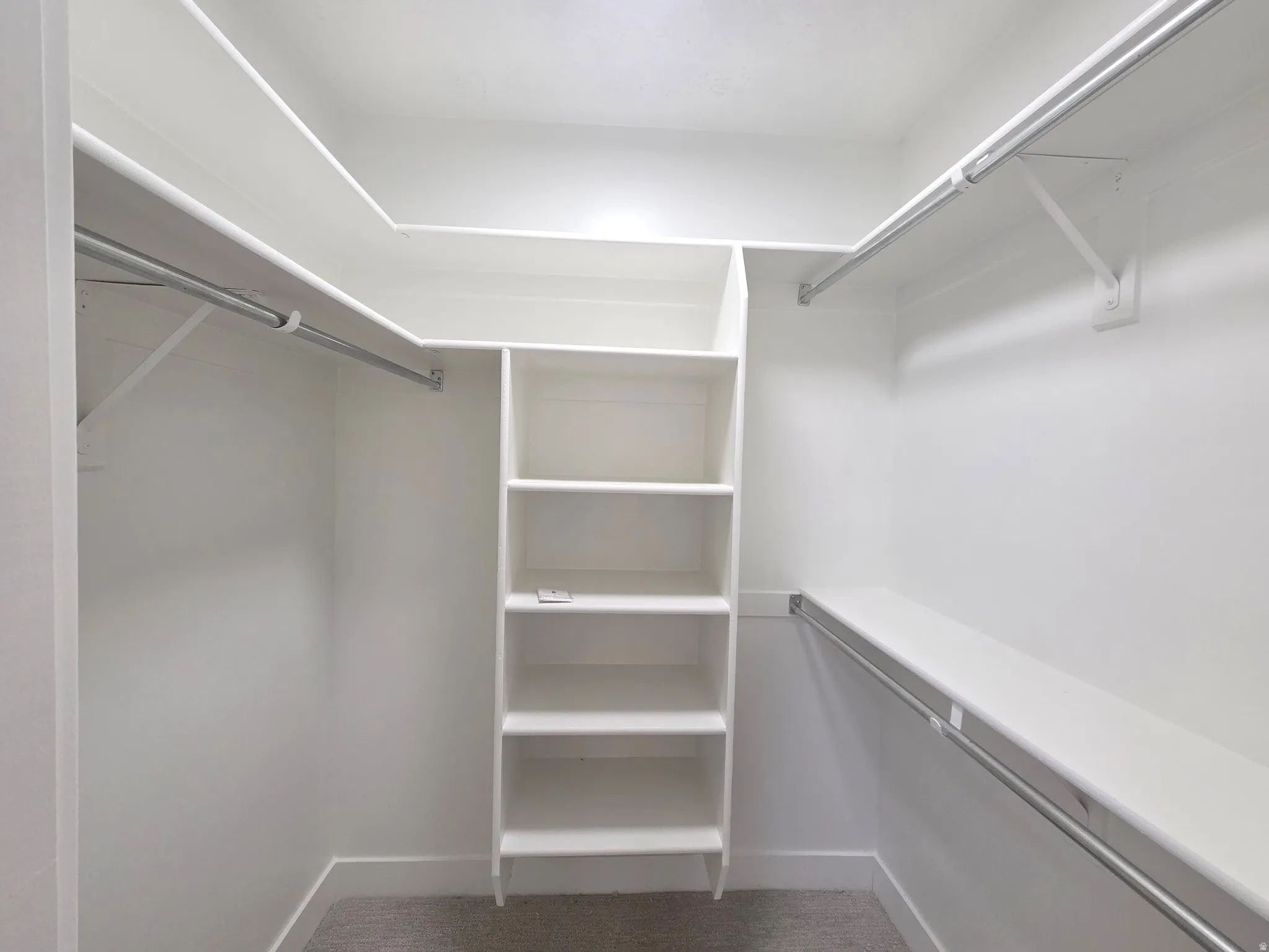 Walk-in closet with built-in shelving, multiple hanging rods, and an integrated shelf