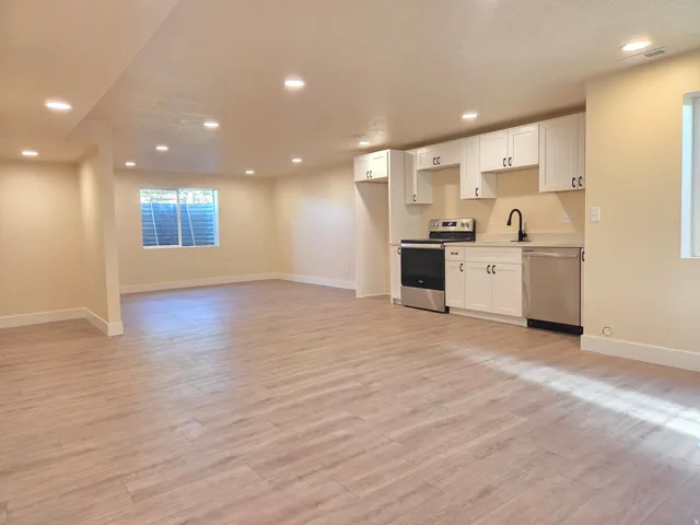 Open-concept living space featuring wood-finish flooring, recessed lighting, and a window