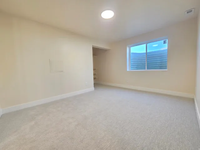 Carpeted room with light-toned walls, white trim, a fixed window, and a ceiling-mounted light fixture