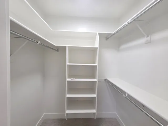 Walk-in closet with built-in shelving, multiple hanging rods, and an integrated shelf