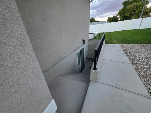 Concrete exterior stairs with black metal handrailing, leading to a sliding glass door