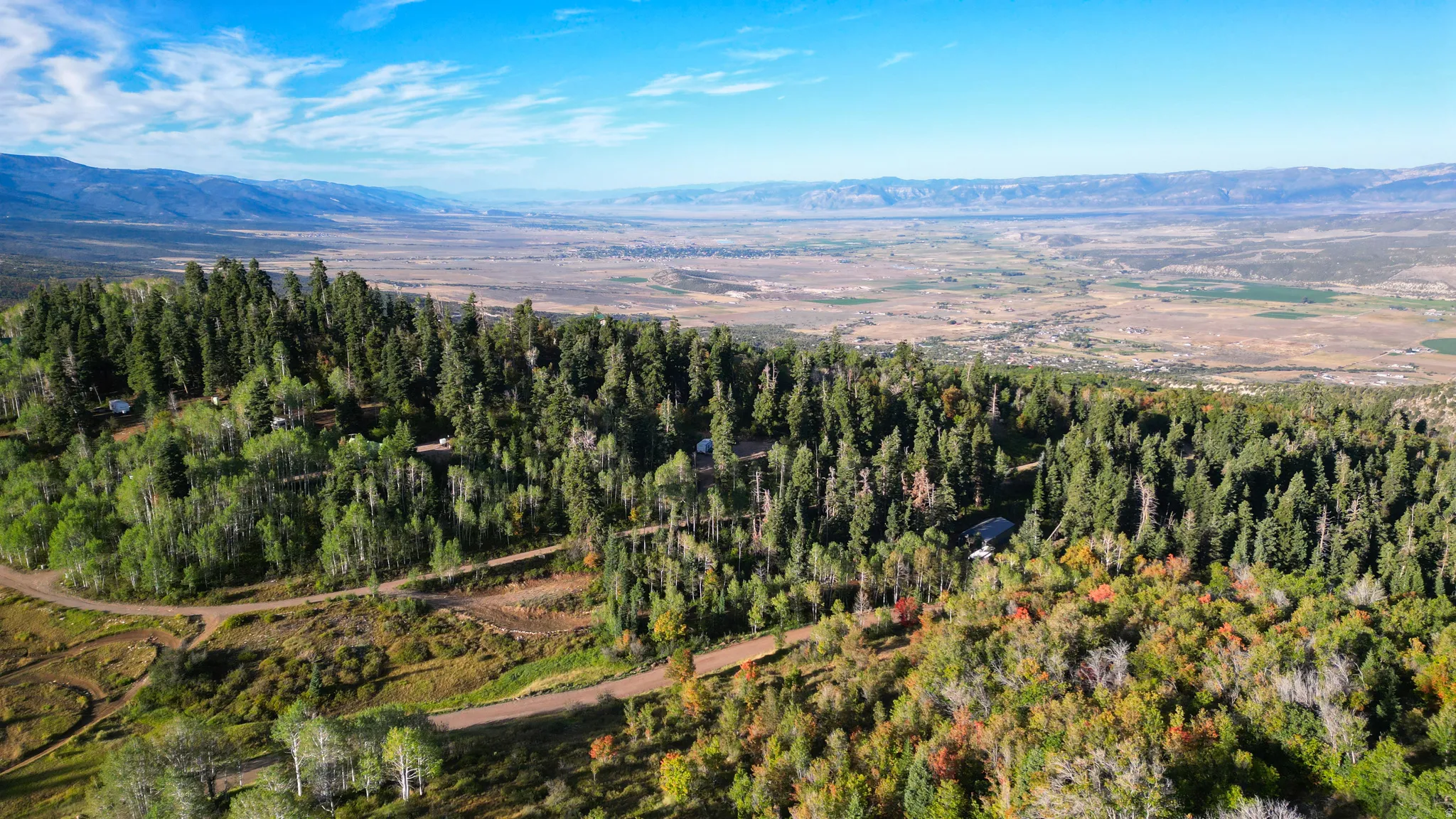 Wooded hillside setting with distant valley and mountain backdrop