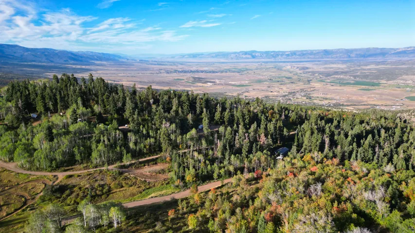 Wooded hillside setting with distant valley and mountain backdrop