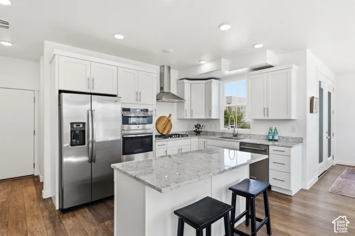 Gourmet kitchen with white cabinetry, stainless steel appliances, wood-finish flooring, and a center island with a granite countertop