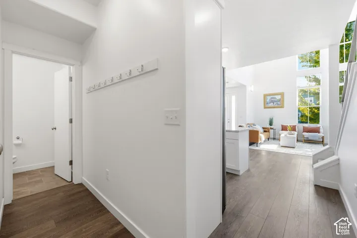 Vaulted ceilings, expansive windows, laminate flooring, white walls, and a built-in coat rack