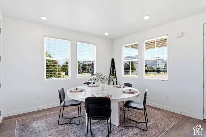 Recessed ceiling lighting, multiple windows with blinds, laminate flooring, and white walls