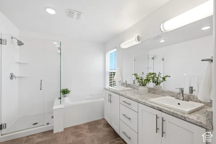 large primary suite bathroom with glass-enclosed shower, built-in bathtub, double vanity with surface-mount sinks, granite-look countertop, and tile flooring