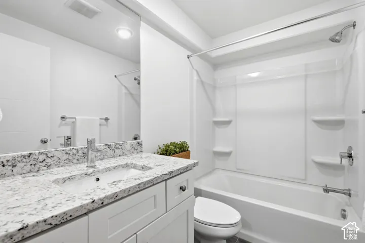 Bathroom featuring a vanity with a light-toned speckled countertop, an integrated rectangular sink, a chrome-finish faucet, and a shower-over-tub combination with a white surround