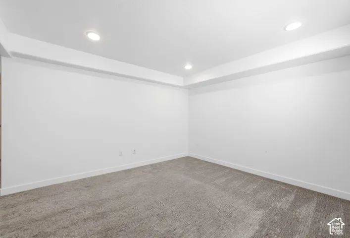 Recessed lighting illuminates the space, featuring clean white walls and a gray patterned carpet