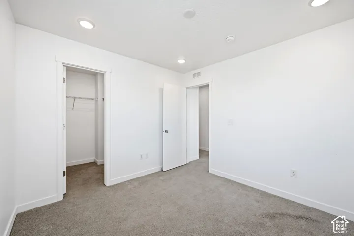 Neutral wall color, recessed ceiling lighting, carpeted flooring, and built-in closet with wire shelving