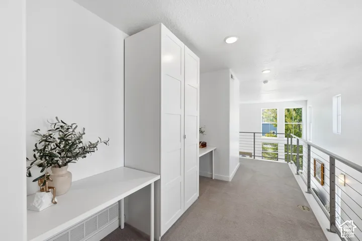 Integrated white cabinetry, built-in desk, contemporary cable railing, recessed lighting, and carpeted flooring