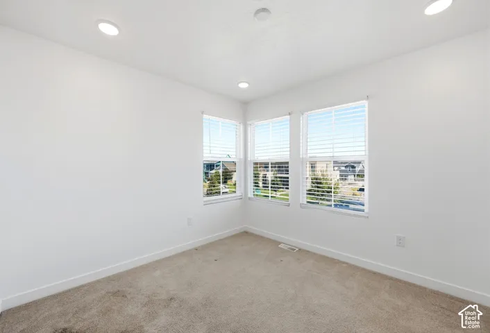 Recessed lighting, multiple windows with blinds, and neutral carpet flooring