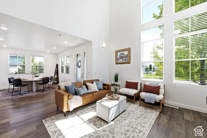 Tallt ceilings with expansive windows, recessed lighting, laminate flooring, and an open-concept living area