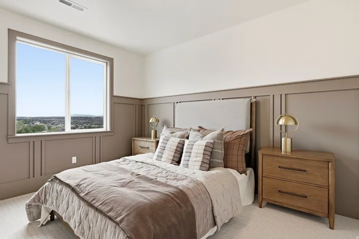 Expansive window offering distant scenery, wall paneling, upholstered headboard, and two wood-finish nightstands