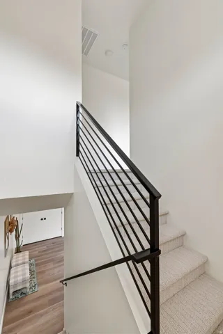 Staircase featuring a modern black metal railing and a handrail