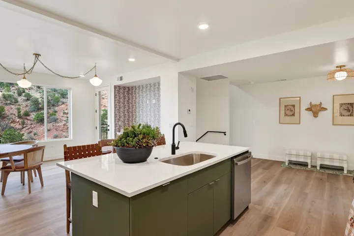 Open concept kitchen and living area featuring a central island with an integrated sink, stainless steel dishwasher, and white countertops