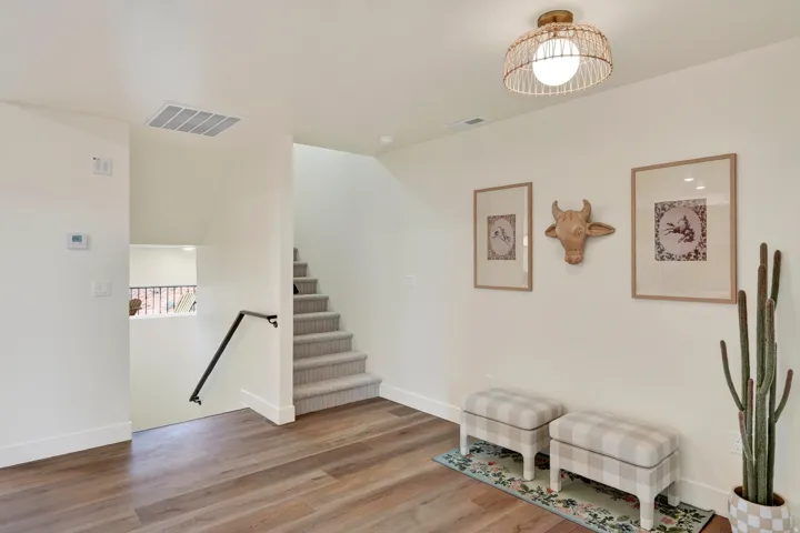 Wood-finish flooring, staircase with carpeted treads, and a black handrail